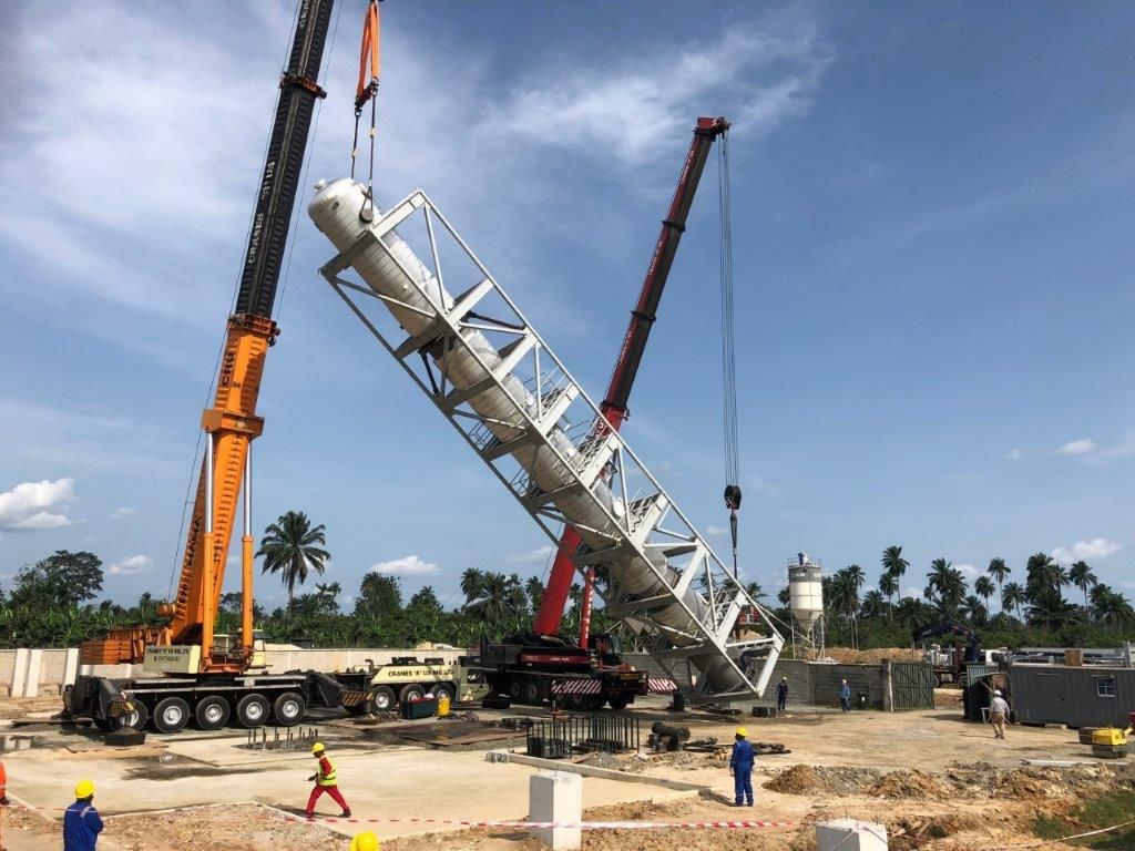 The steel tower raised to roughly forty-five degrees between two mobile cranes, with the ground crew standing well clear.