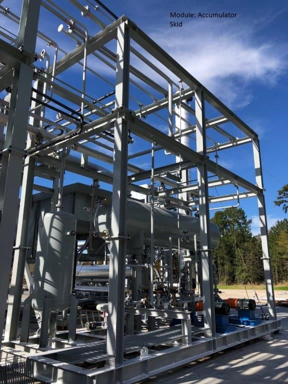A steel-framed process module containing a horizontal accumulator vessel and pipework, standing in a fabrication yard.