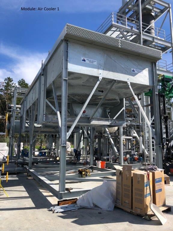 A large air-cooler module on a steel frame with access walkways, in a fabrication yard.