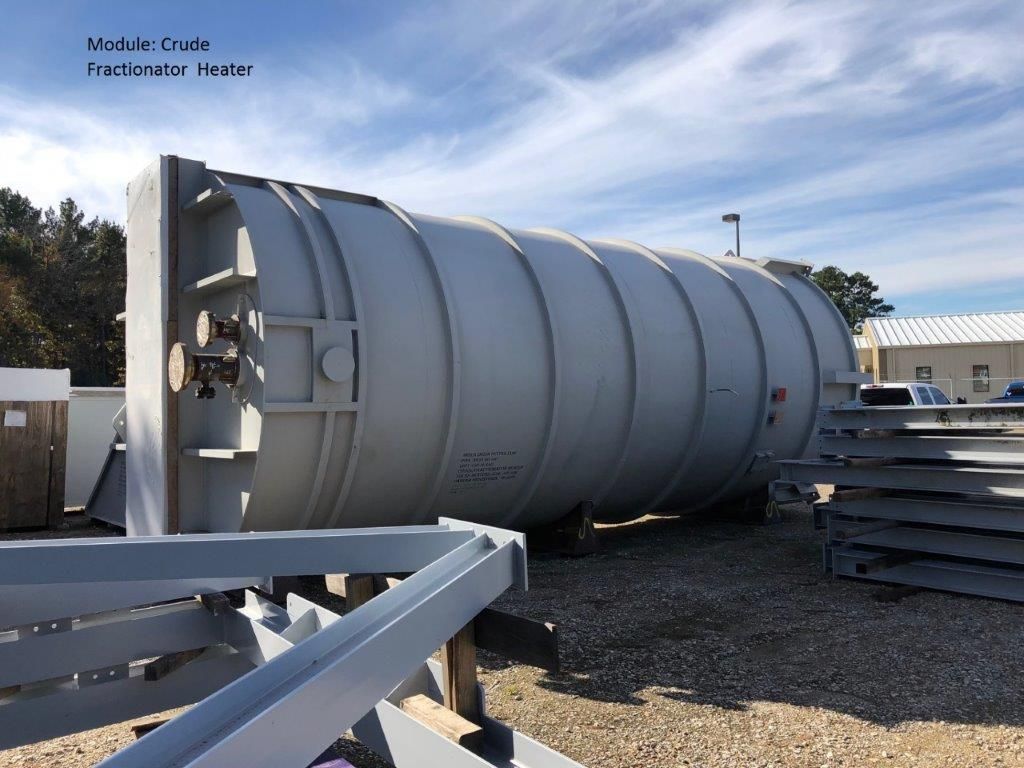 A large cylindrical crude fractionator heater lying horizontally on supports in a fabrication yard.