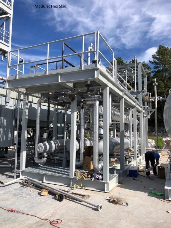 A heat exchanger skid on a two-level steel frame with access stairs and platforms.