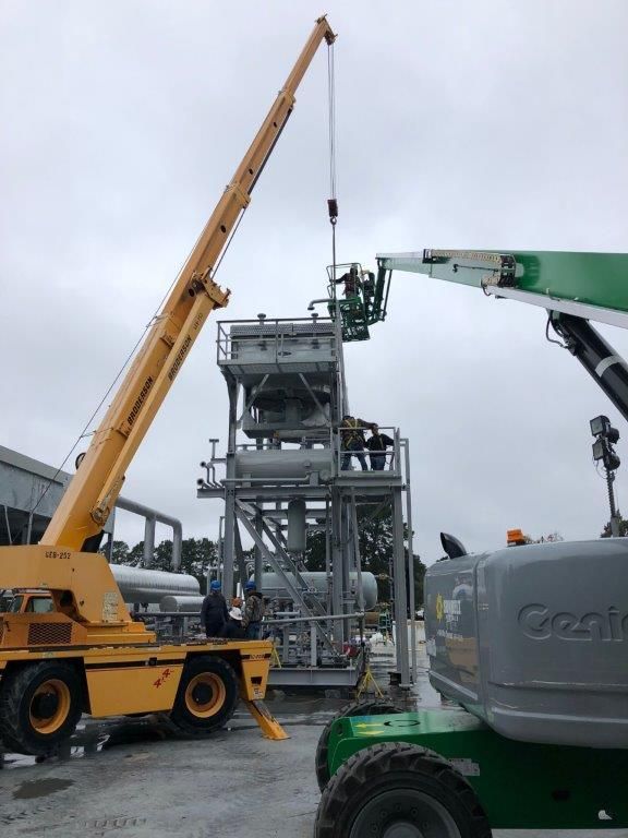 A mobile crane and a green access platform working alongside a process module in a fabrication yard.