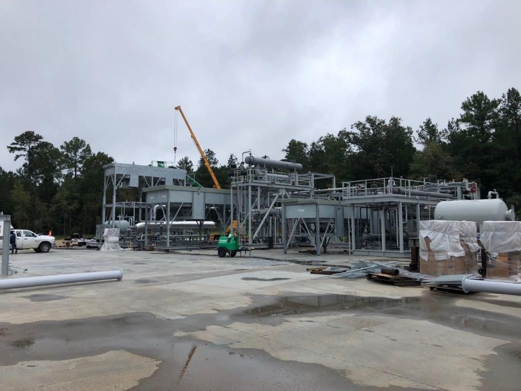 Process modules and air coolers standing in a fabrication yard with a mobile crane working among them.